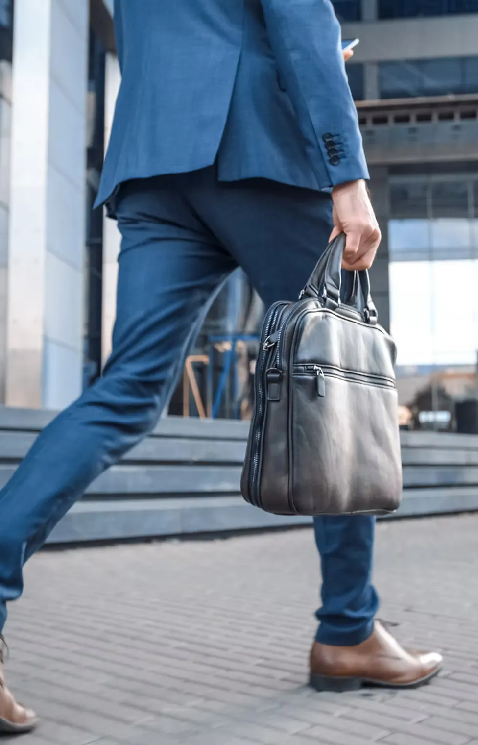 Một người đàn ông đang cầm vali và đi bộ trên đường phố. Hình ảnh này thể hiện sự tự tin và quyết đoán.